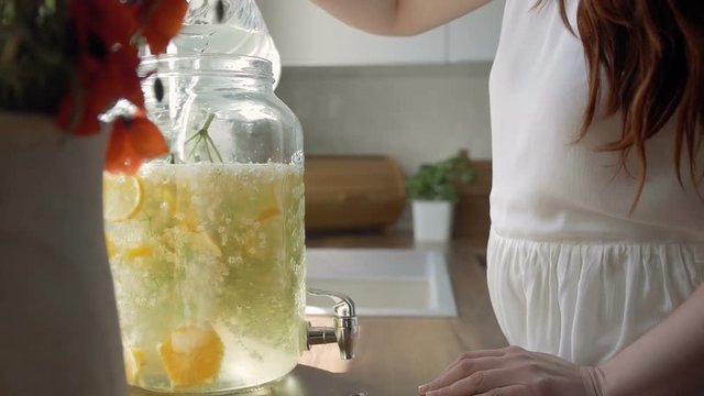 Young woman pouring water on freshly made lemonade, slow motion