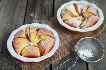 Homemade cottage cheese pie with peaches on wooden table with strainer and whisk