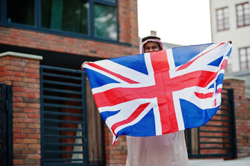 Middle Eastern arab man posed on street with Great Britain flag. England and Arabian countries...