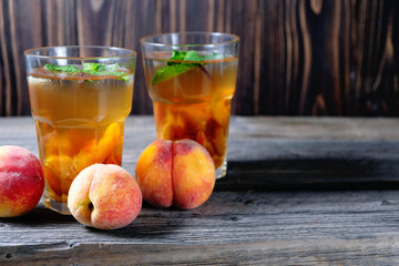Peach ice tea in a glass with mint on wooden table