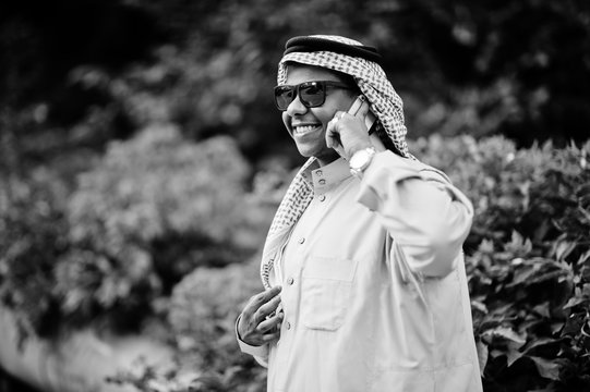 Middle Eastern arab business man posed on street with sunglasses, speaking on mobile phone.