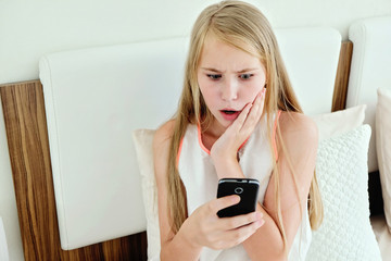 shocking Teenage Girl Lying On Bed Using A Mobile Phone