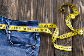 jeans, centimeter on a wooden background. diet. waist
