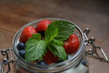 Joghurt mit Blaubeeren, Erdbeeren und Minzeblättern in einem Weckglas