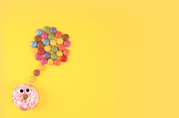 Colorful glazed donuts with funny eyes on yellow background.
