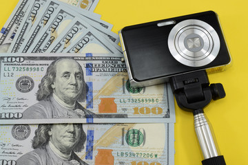 money (dollars) and a photo camera on a yellow background