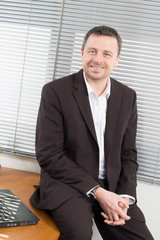 handsome businessman sitting by his desk in office