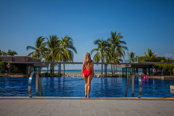 Beautiful woman getting out of a swimming pool. beautiful long hair tanned girl posing by blue pool water, ocean and sky Phuket, Thailand
