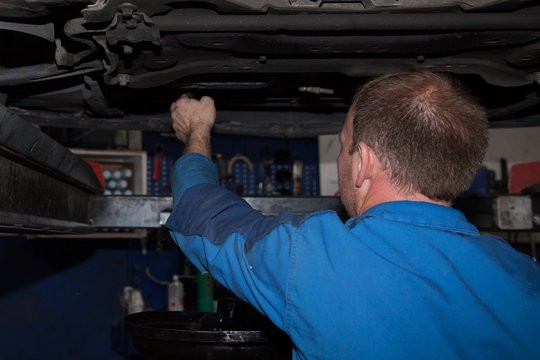 Auto mechanic working in garage car service maintenance and people concept