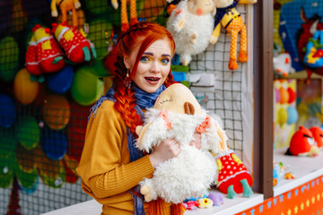 young cheerful red-haired girl posing  in the amusement Park. Portrait of a woman with bright makeup and long red hair. She poses, has fun and plays.