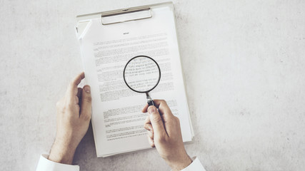 Man hands looking document with magnifying glass - obrazy, fototapety, plakaty
