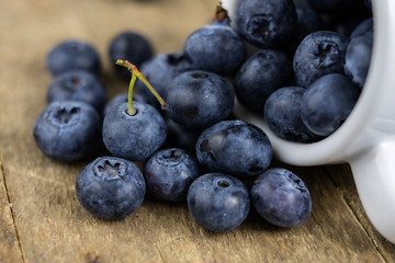 Ripe blueberry fruit in a container on a wooden kitchen table. Fruit prepared for dessert.