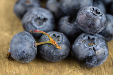 Ripe blueberry fruit in a container on a wooden kitchen table. Fruit prepared for dessert.