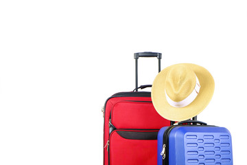 Red textile suitcase & blue hard shell luggage with straw hat hanging on extended telescopic handle, white decorative texture wall background. Couples retreat trip concept. Close up, copy space.