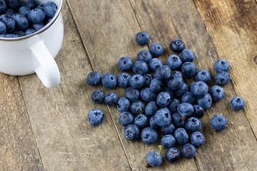 Ripe blueberry fruit in a container on a wooden kitchen table. Fruit prepared for dessert.
