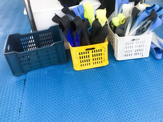 Two plastic boxes, baskets with multi-colored rubber diving flippers for swimming, diving equipment...