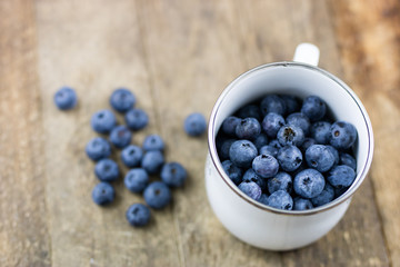 Ripe blueberry fruit in a container on a wooden kitchen table. Fruit prepared for dessert.