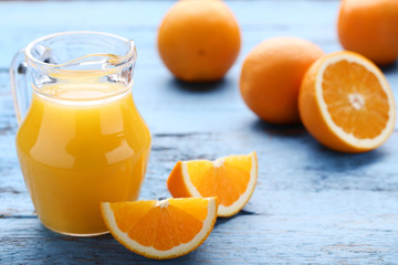 Orange fruit with jug of juice on blue wooden table