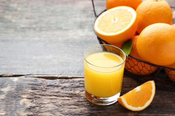 Orange fruit with glass of juice on grey wooden table
