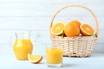 Orange fruit with jug and glass of juice on wooden table