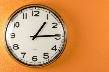 Fototapeta na wymiar white clock on an orange wall