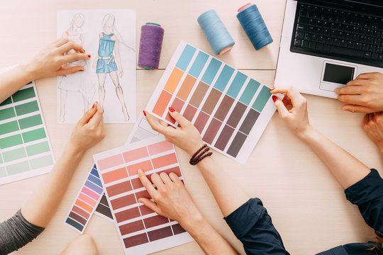 fashion designers developing new collection. creative team meeting at design studio. male and female coworkers selecting colors and sewing strings for dresses. 