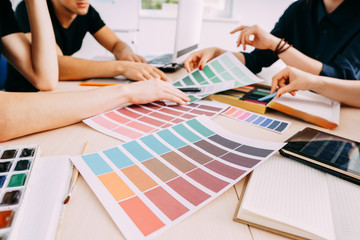 graphic designers working with color samples discussing and choosing colors. creative team at design studio