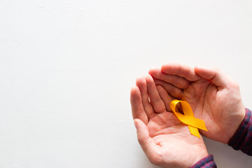 man holds a yellow ribbon on a white background with space for text