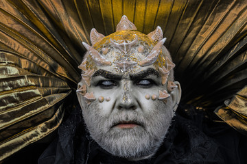 Man with thorns or warts, face covered with glitters. Senior man with white beard dressed like...