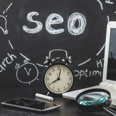 SEO Search engine optimization concept Magnifying glass, clock, smartphone on a black background with an inscription SEO Close up