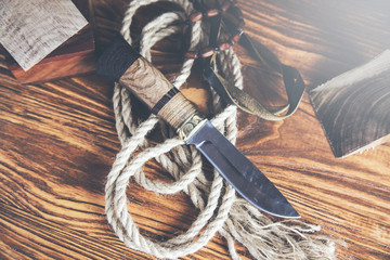 Pocket knife with rope on wooden table - obrazy, fototapety, plakaty