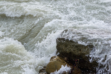 pebble stones on the sea beach, the rolling waves of the sea with foam