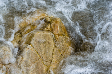 pebble stones on the sea beach, the rolling waves of the sea with foam