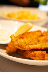 Pile of piping hot and crispy delicious Fish and chips or fried battered fish and hot potato fries served with tartar sauce.