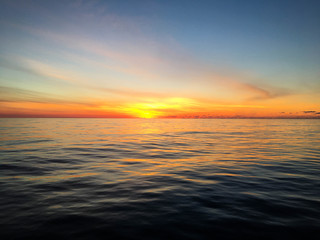 Fototapeta na wymiar Colorful sky as dawn breaks over calm waters in the Atlantic Ocean