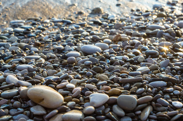 pebble stones on the sea beach, the rolling waves of the sea with foam