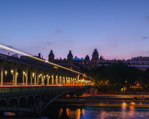 Night shot of the Bir-hakeim bridge in Paris with lights in long exposure of red, orange and yellow tones giving a sense of movement