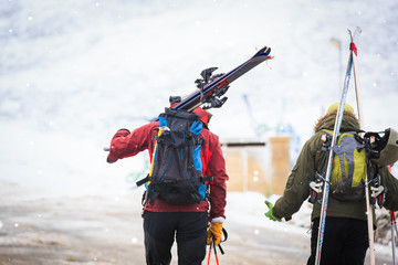 Back view of skiers carrying skis