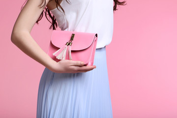 Young woman with handbag on pink background