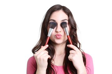 Beautiful woman with makeup brushes on white background