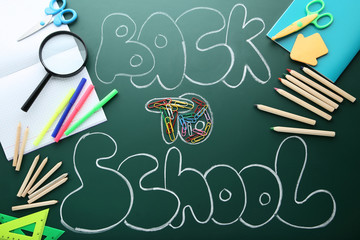 Inscription Back To School on chalkboard with school supplies
