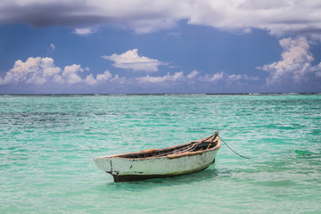 Naklejka na ściany i meble old fisherman boat moored in the blue ocean under cloudy sky, Mauritius island