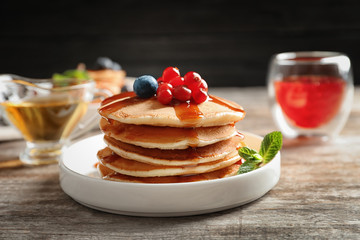 Stack of tasty pancakes with berries and syrup on table © New Africa