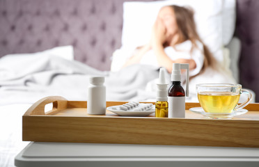 Different cold remedies and sick woman on background