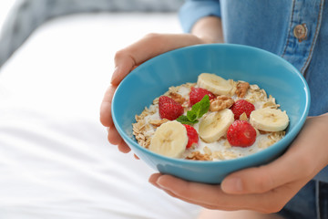 Woman holding bowl with delicious oatmeal and fruits, closeup. Healthy diet