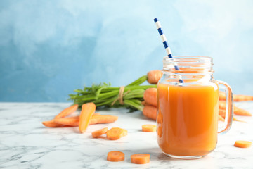 Mason jar with carrot juice and fresh vegetable on table