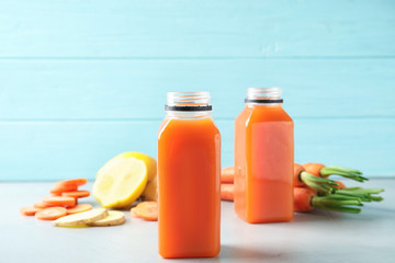 Bottles with carrot juice and fresh ingredients on table