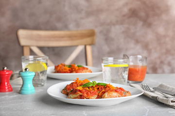 Plate with stuffed cabbage leaves in tomato sauce on table