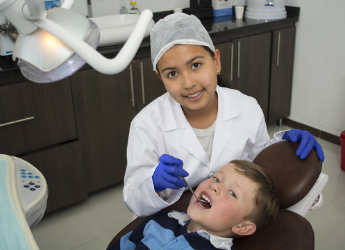 Little boy having teeth checked by doctor girl.