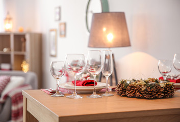 Set of dinnerware and Christmas wreath on table indoors